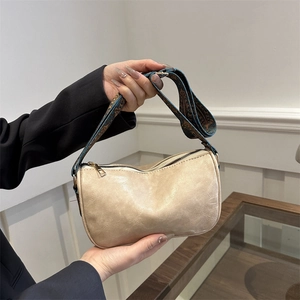 Large beige faux leather tote with patterned wide strap in a modern indoor setting