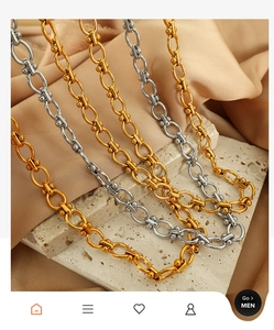 Detailed close-up of gold and silver ball link chain necklaces on a beige stone surface