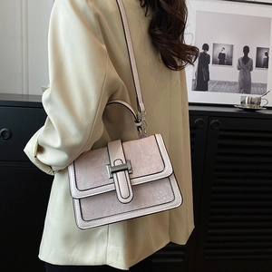 Close-up of floral print flap and metallic lock on a beige crossbody handbag