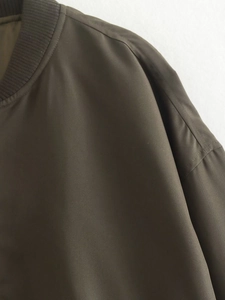 Détail de veste vert olive avec encolure côtelée et texture en tissu synthétique lisse