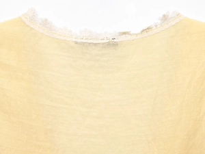 Detailed close-up of white lace trim on yellow fabric neckline for women tops
