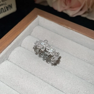 Detailed macro view of silver hollow flower ring with zircons on grey velvet box