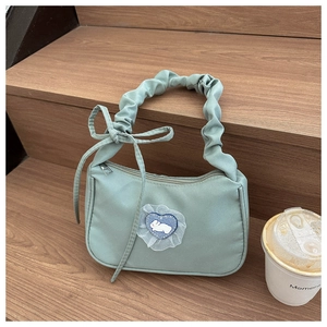 Detail of light green shoulder bag featuring a lace heart rabbit patch on wooden stairs