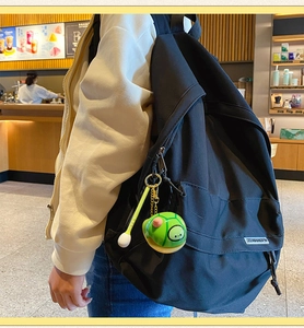 Niedlicher grüner Schildkröten-Anhänger an einem schwarzen Rucksack in einem Café
