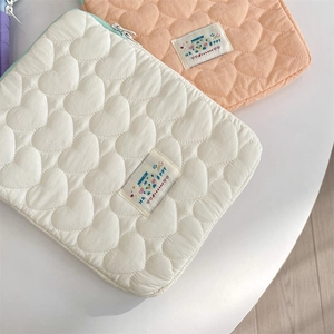 Detalle del patrón de corazón acolchado en fundas para portátiles crema y melocotón