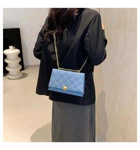 Blue denim quilted bag with gold chain strap shown on model for back-view perspective