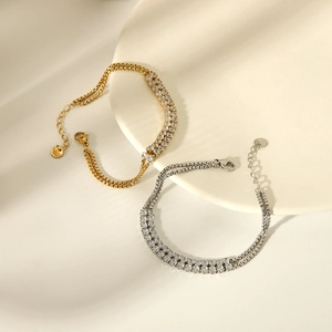 Macro detail of gold and silver square zircon bracelets with 18K box chain on ceramic tray