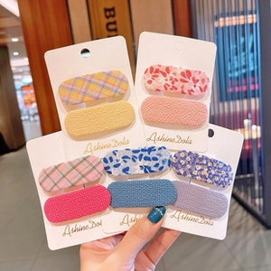 Close-up of assorted colorful fabric oval hair clips on display cards in hand