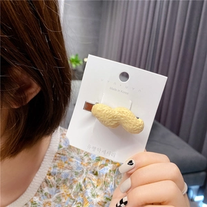 Detailed view of the peanut-shaped hair clip with textured shell on a white display card