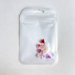 Assorted DIY resin rose flower charms for nail art in a clear plastic storage bag
