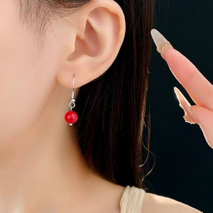 Gros plan d'un mannequin portant d'élégantes boucles d'oreilles perles rouges
