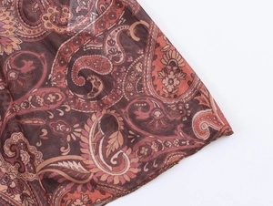 Détail du tissu en maille avec imprimé paisley marron et orange et texture légère