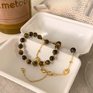 Detail of 18K gold plated tiger eye bead bracelet set with heart pendant in a jewelry box