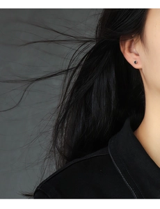 Close-up of model wearing black square zircon stud earring on a dark background