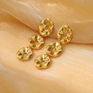 Three-tier wavy drop earrings in polished gold stainless steel on champagne silk background