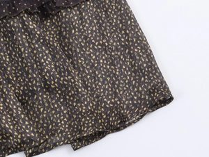 Macro view of dark fabric featuring golden polka dots and fine metallic vertical stripes