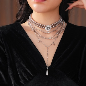 Close-up of multilayer silver necklace featuring square rhinestones and pearl pendants