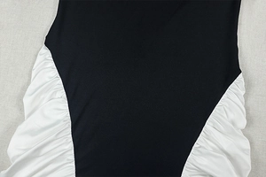 Vue macro détaillée d'une robe moulante noire avec empiècements froncés blancs sur les côtés