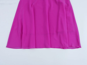 Dettaglio dell'orlo dell'abito in chiffon rosa con trama a pieghe e drappeggio morbido