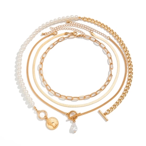 Detailed flat lay of layered gold chains with baroque pearls and portrait coin pendants