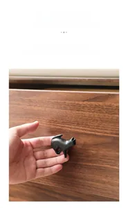 Close-up of black cast iron cat-shaped handle installed on a dark walnut drawer cabinet