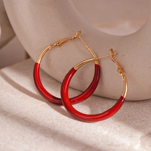 Close-up of vintage red enamel and gold-plated circular hoop earrings on a stone base