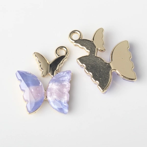 Detail view of purple gradient resin butterfly charms with golden metal backing for DIY