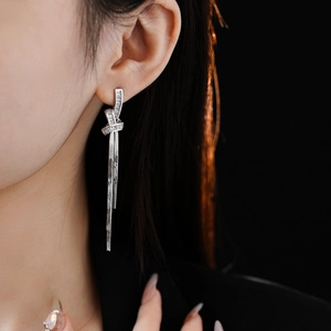 Detail of silver knot earrings with rectangular zircons and hanging tassel chains