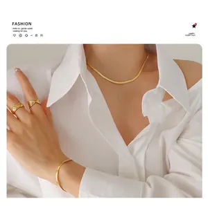 Close-up of minimalist gold snake chain necklace and quilted ring set on a model