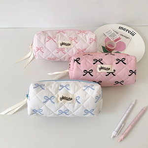 Detailed view of quilted bow pouches in pink and white with elegant ribbon zipper pulls
