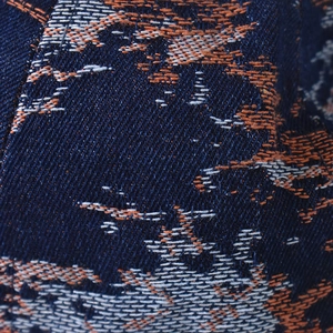Macro shot of denim fabric with orange and gray jacquard embroidery for baseball caps