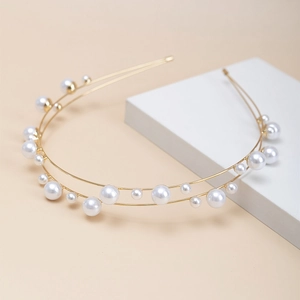 Double-layered gold headband with polished white pearls of varying sizes on a minimalist base