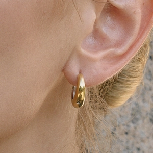 Nahaufnahme eleganter zweifarbiger 18K Goldohrringe an einem weiblichen Ohrläppchen