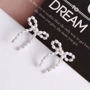 Macro shot of elegant handmade pearl bow earrings with a vintage gold base finish