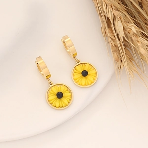 Detail shot of golden sunflower earrings featuring yellow petals on a beige backdrop