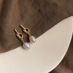 Macro detail of French vintage baroque pearl earrings with elegant gold twisted metal knot