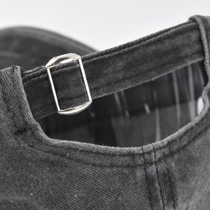 Macro view of adjustable metal buckle and washed cotton texture on dark gray baseball cap