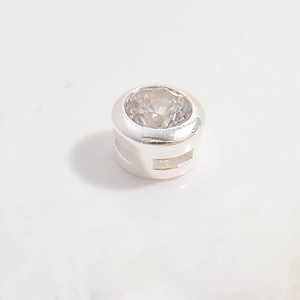 Macro detail of silver round bezel setting with clear cubic zirconia and side hollow design