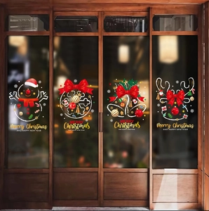 Christmas window decals with reindeer and snowman designs on glass doors with warm lighting