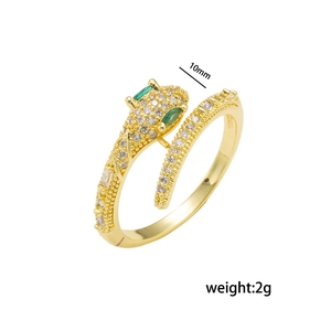 Golden snake ring with green stone eyes and white cubic zirconia accents on white background