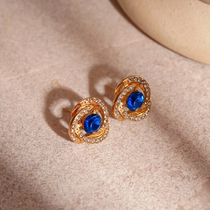Detail view of gold spiral earrings with blue center stone and diamond accents