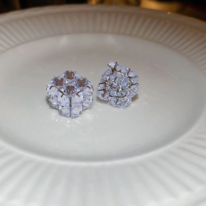Close-up of silver stud earrings featuring cubic zircon cubes on a white ceramic tray