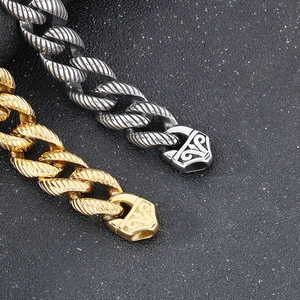 Macro detail of men's chunky 18k gold plated Cuban link chain with textured clasp
