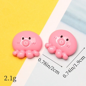 Detailed size view of two pink resin octopus charms on a yellow and blue background