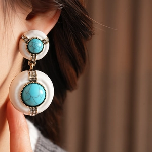 Close-up of vintage resin earrings with turquoise gemstones and rhinestone details