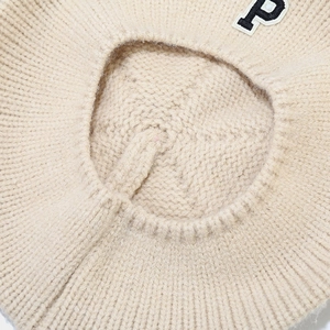 Macro shot of beige knit beret featuring a classic varsity style letter P embroidery patch