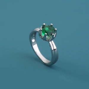 Close-up of a silver ring featuring a round green gemstone in a classic prong setting