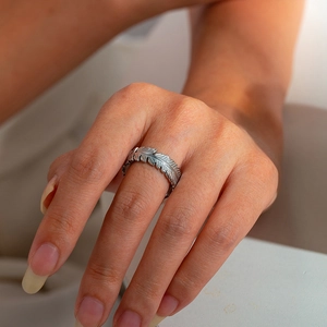Close-up of silver feather titanium steel ring with intricate leaf textures on finger