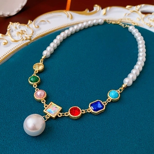 Macro shot of baroque pearl necklace with colorful gemstones on a vintage tray