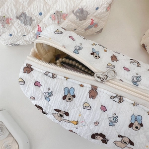 Detailed macro view of quilted cream pencil case with cute dog and elephant cartoon patterns